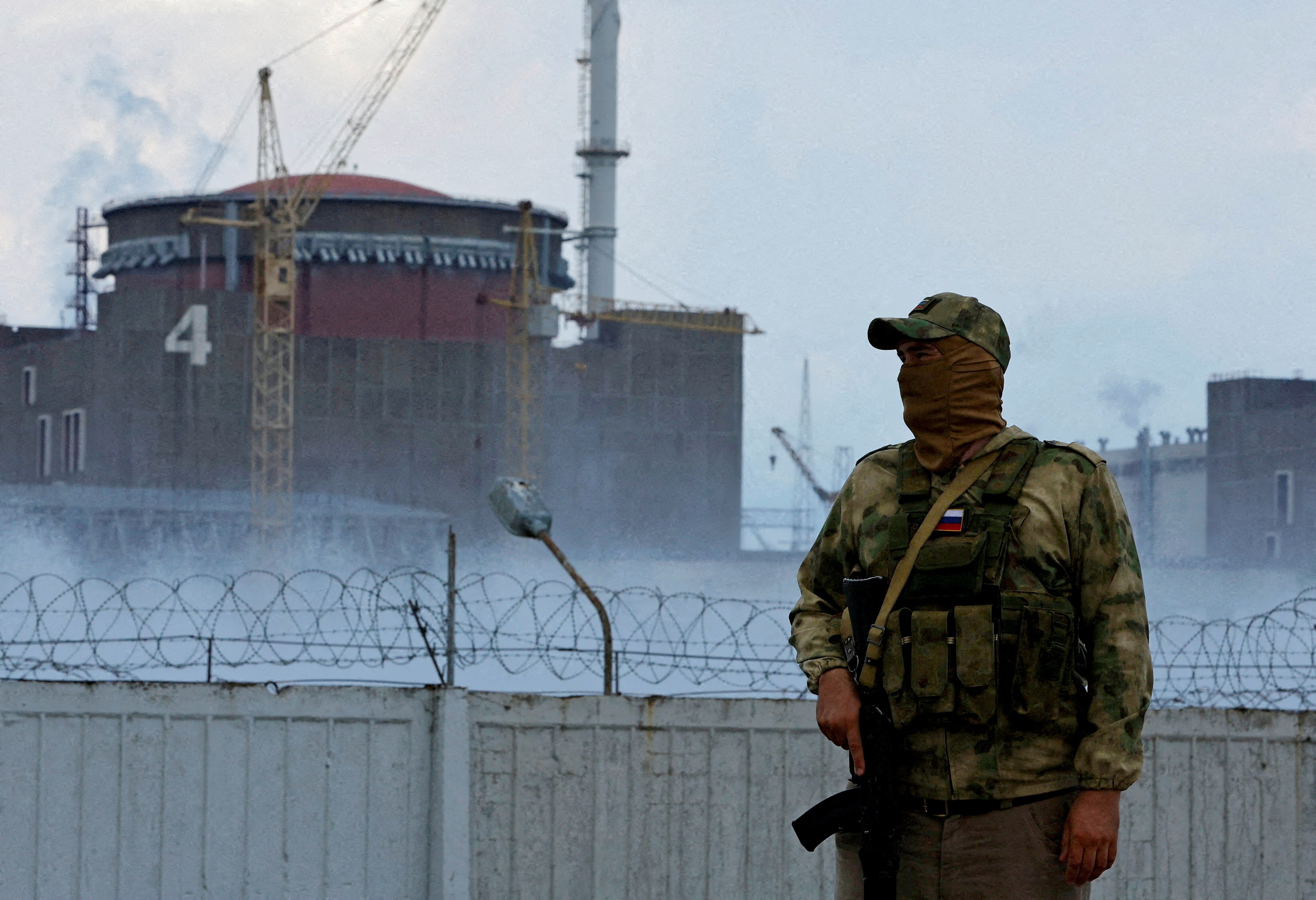 A serviceman with a Russian flag on his uniform stands guard near the Zaporizhzhia Nuclear Power Plant.
