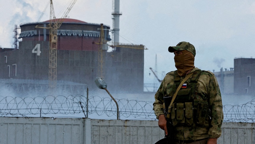 A serviceman with a Russian flag on his uniform stands guard near the Zaporizhzhia Nuclear Power Plant