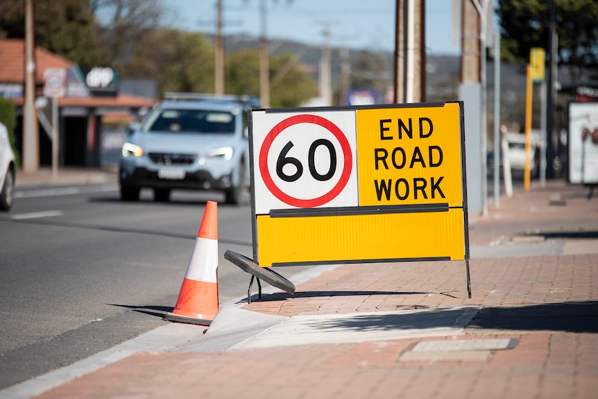 A sign saying End Road Work sits alongside a road.