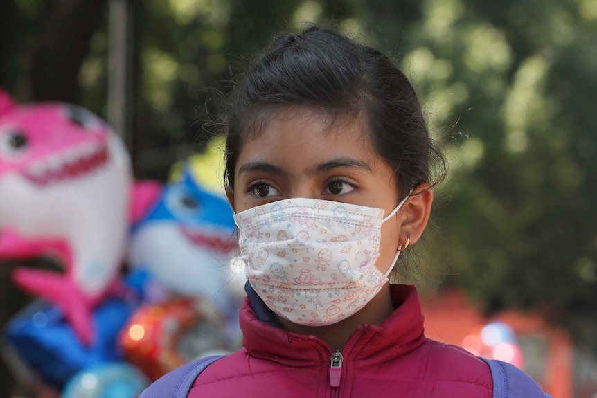 A female child wearing a surgical face mask with a baby pattern on