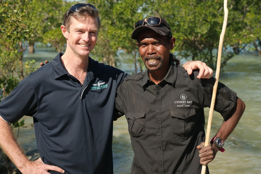 A white and black man standing in mangroves