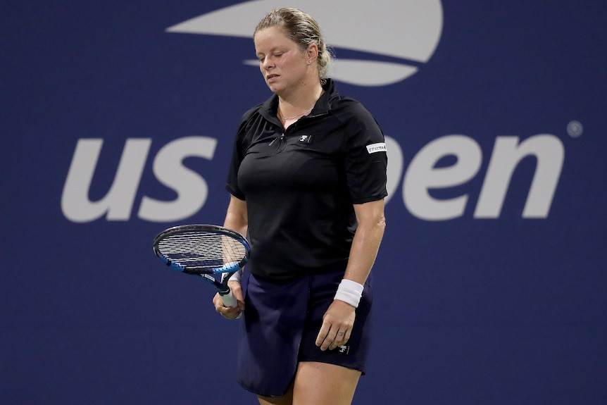 Kim Clijsters looks down at her racquet, wearing a black top