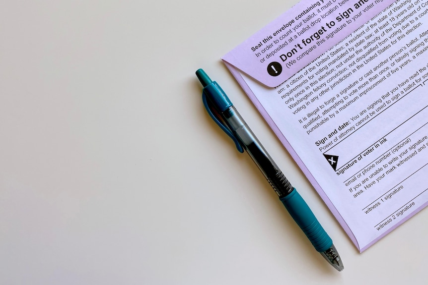 Generic postal voting ballot paper with a green pen beside it on a flat, white surface