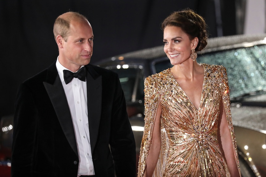 Britain's Prince William, left, and his wife Kate the Duchess of Cambridge arrive, wearing sparkly gold dress and tuxedo