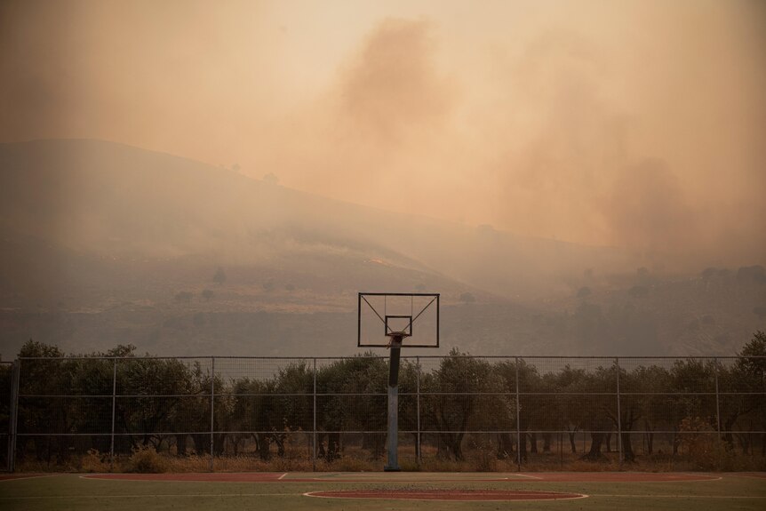 Дым от лесных пожаров покрывает воздух над баскетбольной площадкой возле Лардоса.