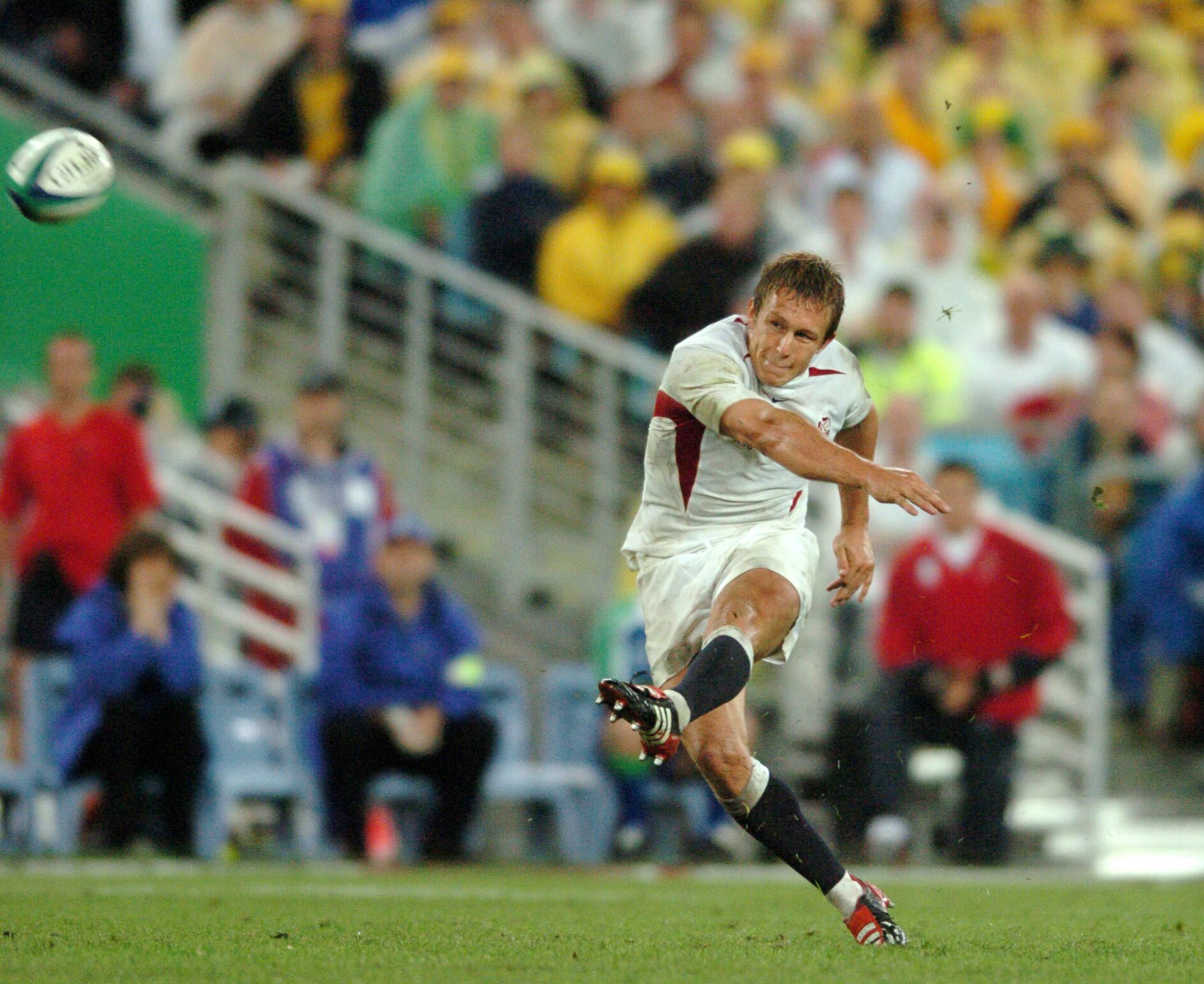 A man in white kicks a rugby union ball