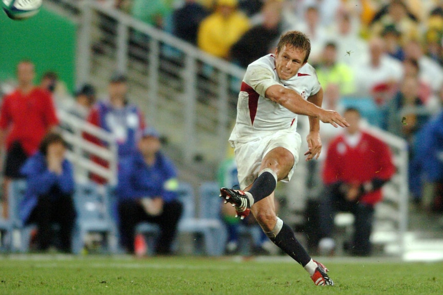 A man in white kicks a rugby union ball