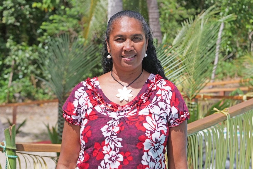 A woman in a red floral shirt smiles at the camera.
