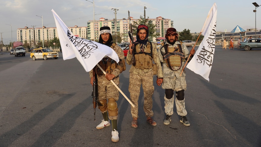 Three Taliban fights stand together with white flags. 