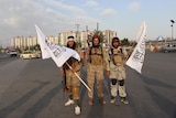 Three Taliban fights stand together with white flags. 
