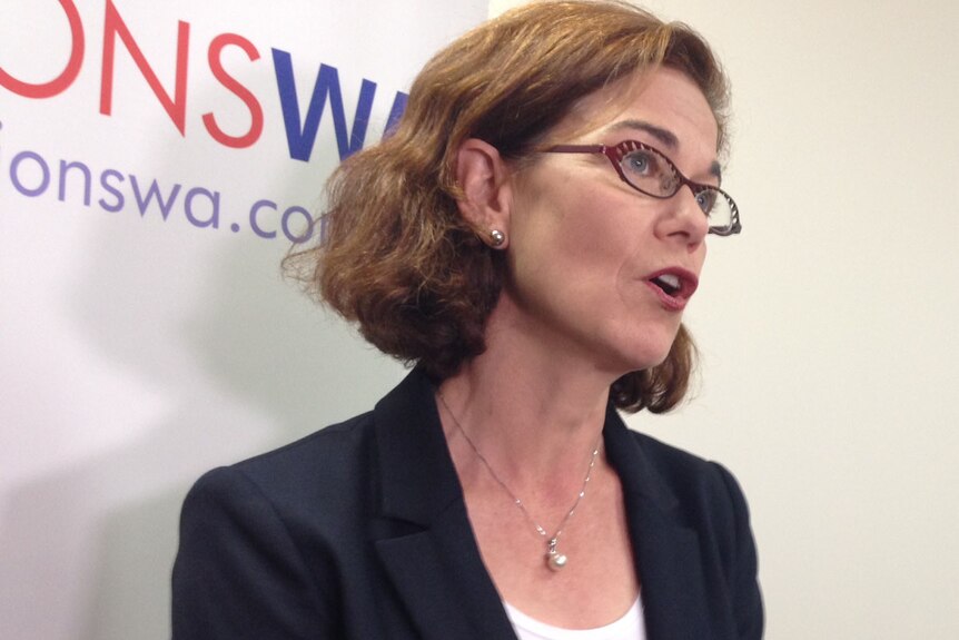 Woman in a suit with glasses on standing in front of a Unions WA sign
