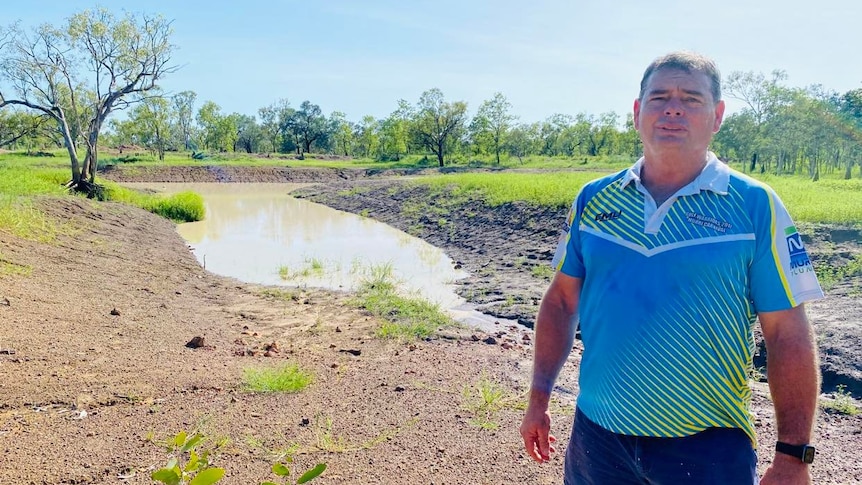 Man stands in front of an empty dam.