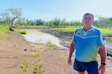 Man stands in front of an empty dam.