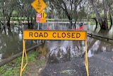 A road closed sign stands infront of floodwaters