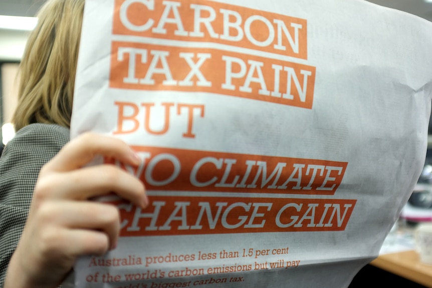 A woman reads The Australian with full page anti-carbon tax ads.