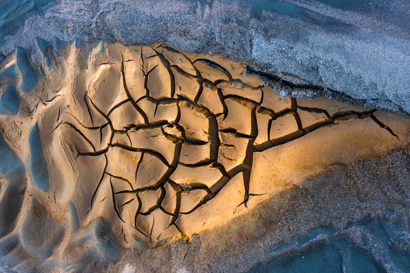 An overhead shot of a sandbank in a frozen river.