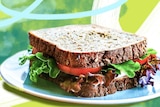 A salad sandwich on a plate made with grain bread, tomato and lettuce makes a healthy packed lunch for work.