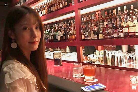 Park Gyu-ri sitting at a bar with a drink in front of her