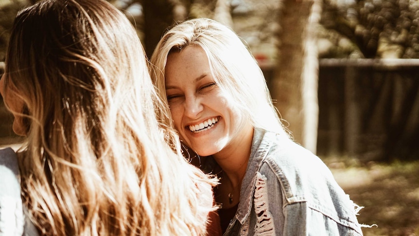 Woman laughing with a female friend for a story about women sharing what it's like to live childfree and have zero regrets.