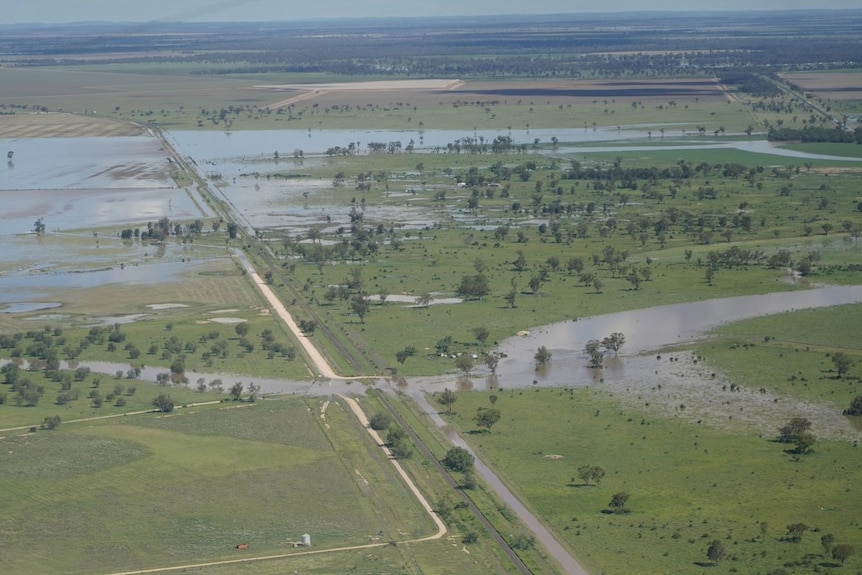 An aerial shot of flooded grass areas over a road.