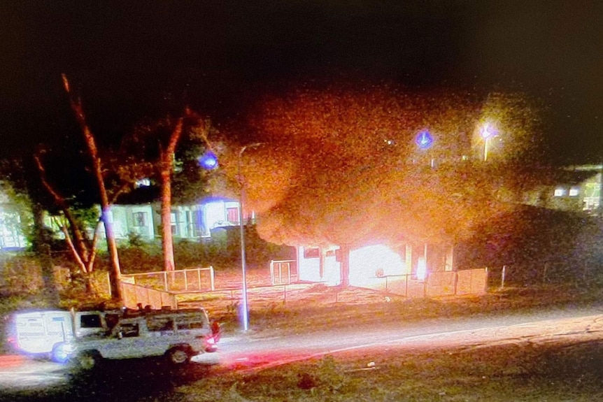 Police patrol at night while a home burns in Aurukun.