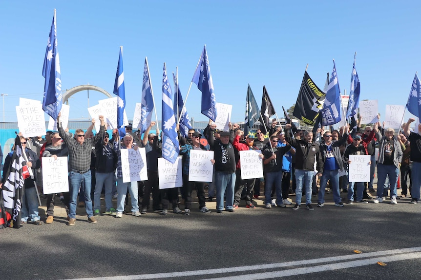 Union men protest with flags and signs.