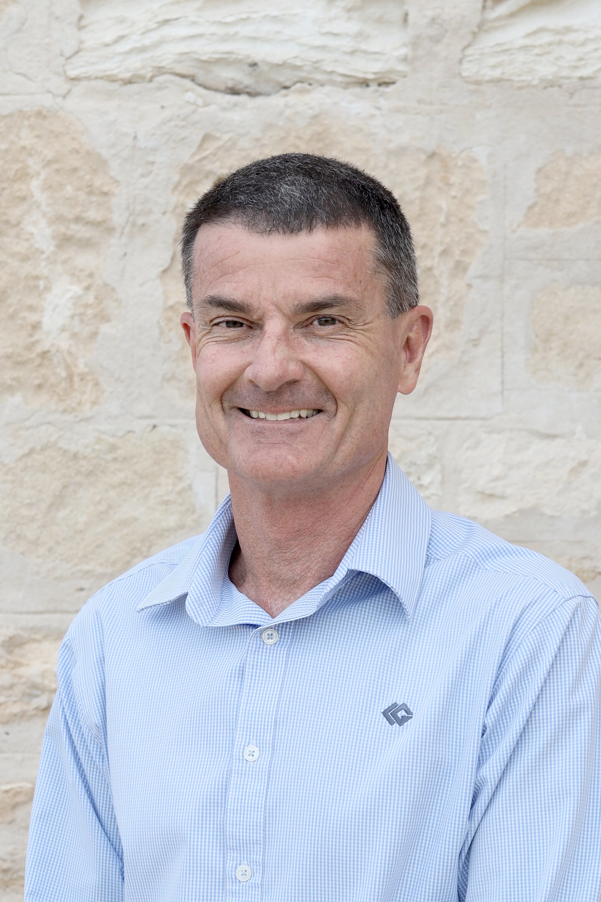 A man wearing a blue shirt smiling at a camera. 