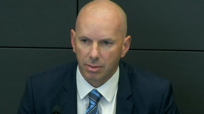 Dressed in suit and tie, Craig Holland sits before a microphone at a hearing of the royal commission.