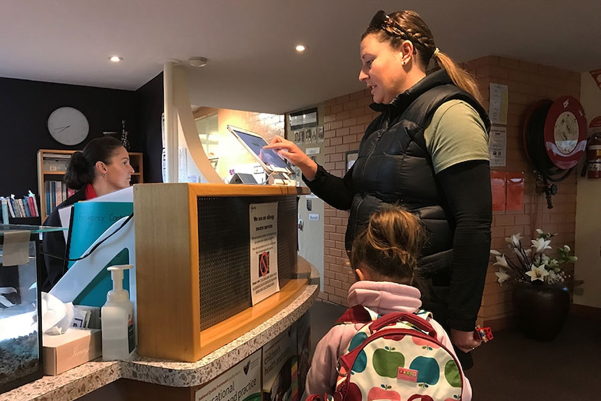 Sarah Walton signs in her daughter at child care