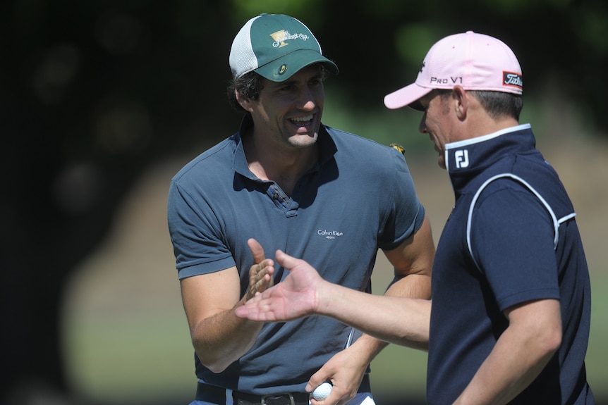 Andy Lee and Shane Warne high-five on a golf course.