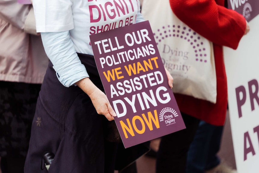 Voluntary euthanasia supporter holds a sign in support of voluntary assisted dying