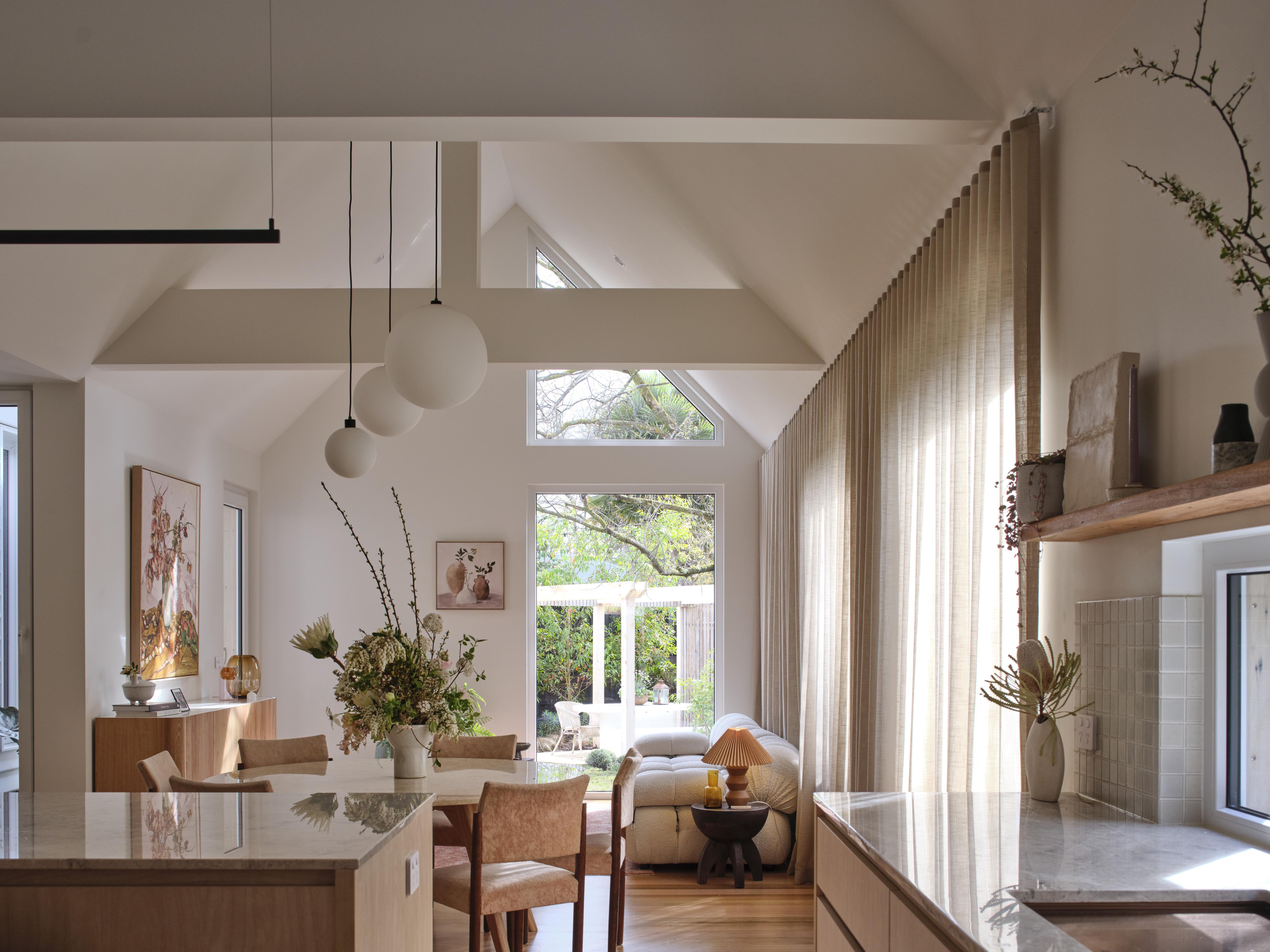 A shot looking down the length of a living room filled with light, round ceiling pendant lights hang from the roof 