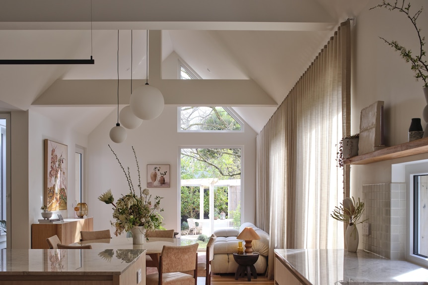 A shot looking down the length of a living room filled with light, round ceiling pendant lights hang from the roof 