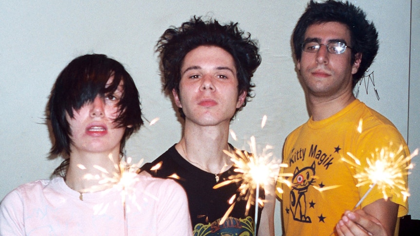 Three members of Yeah Yeah Yeahs hold up lit sparklers
