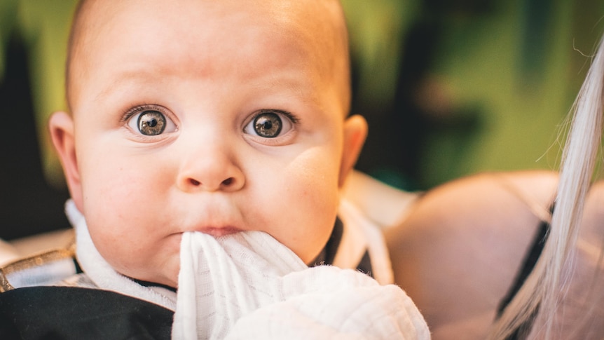 Baby sucking on a sheet for a story about baby names and cultural appropriation.