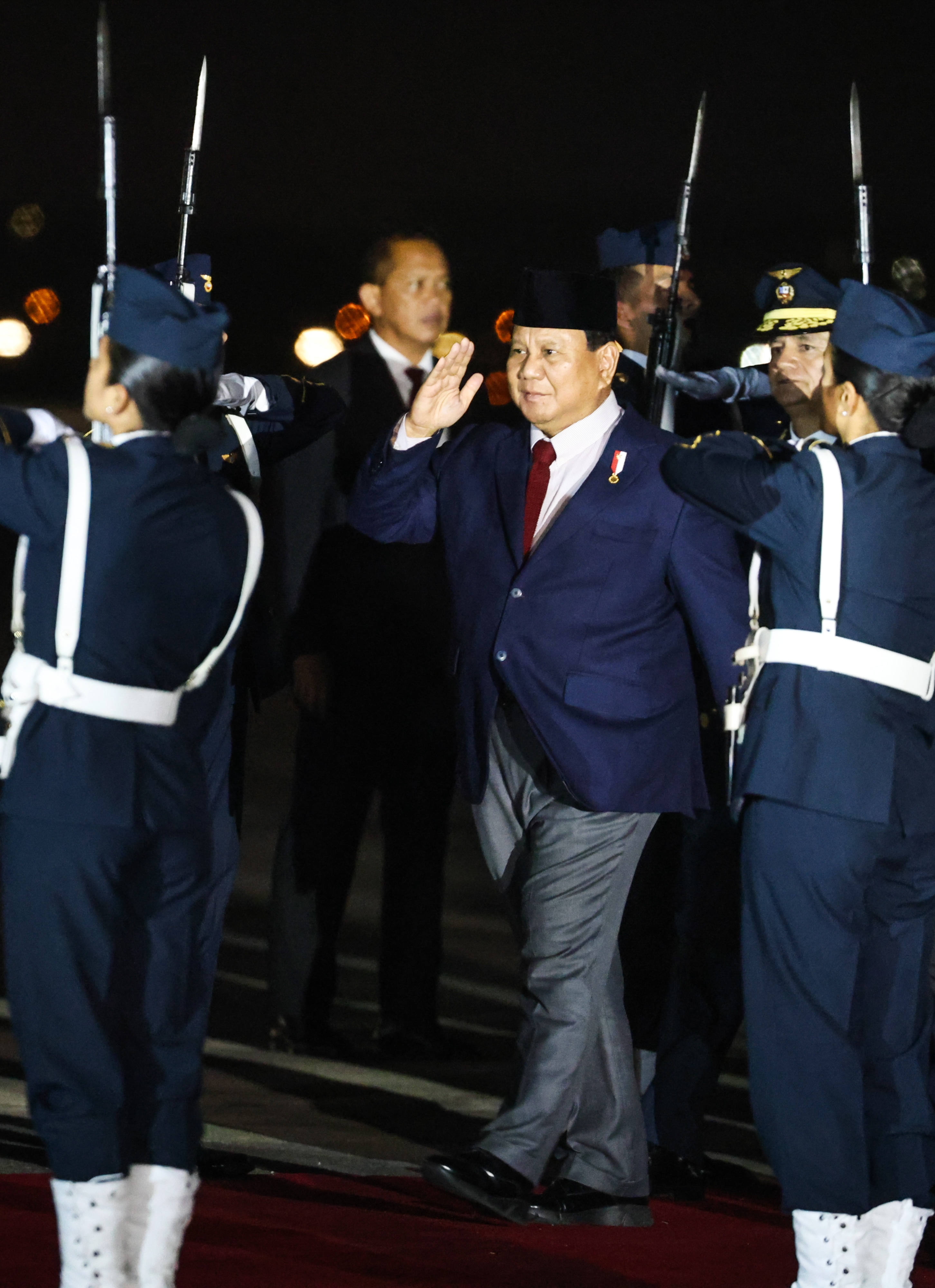 man wearing dark blue suit salutes as he depart a plane 