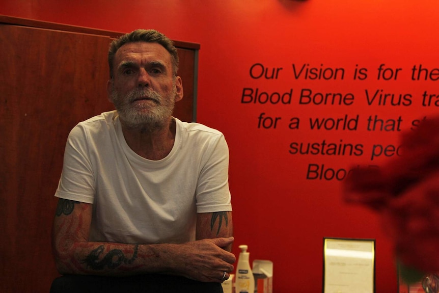 A photo of Dan Alderman in the NTAHC office in front of a wall with a mural.