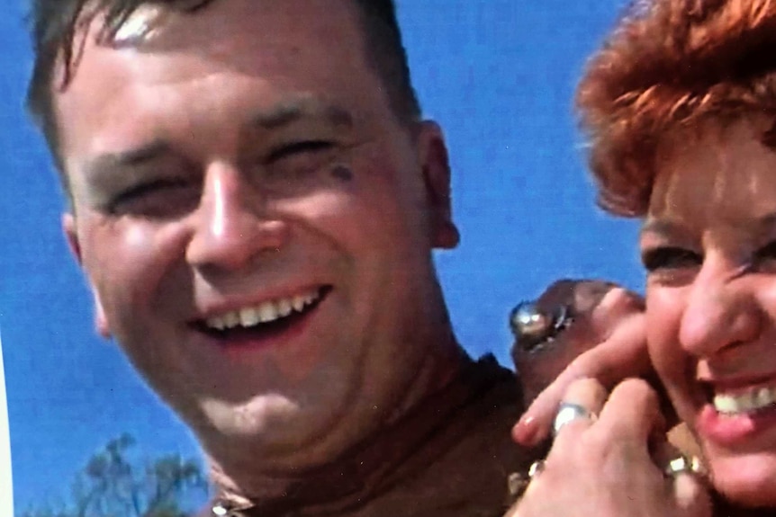 A young Bertrand Cadart in biker costume smiles with a lady on set of Mad Max.