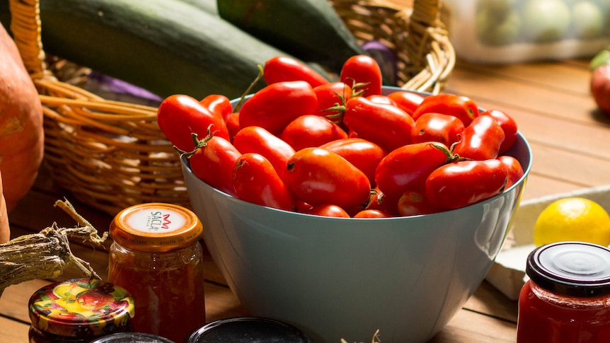 A basket of vegetables sits on a table.