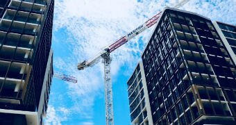 A Meriton crane is shown hanging over tall residential apartments in Sydney.