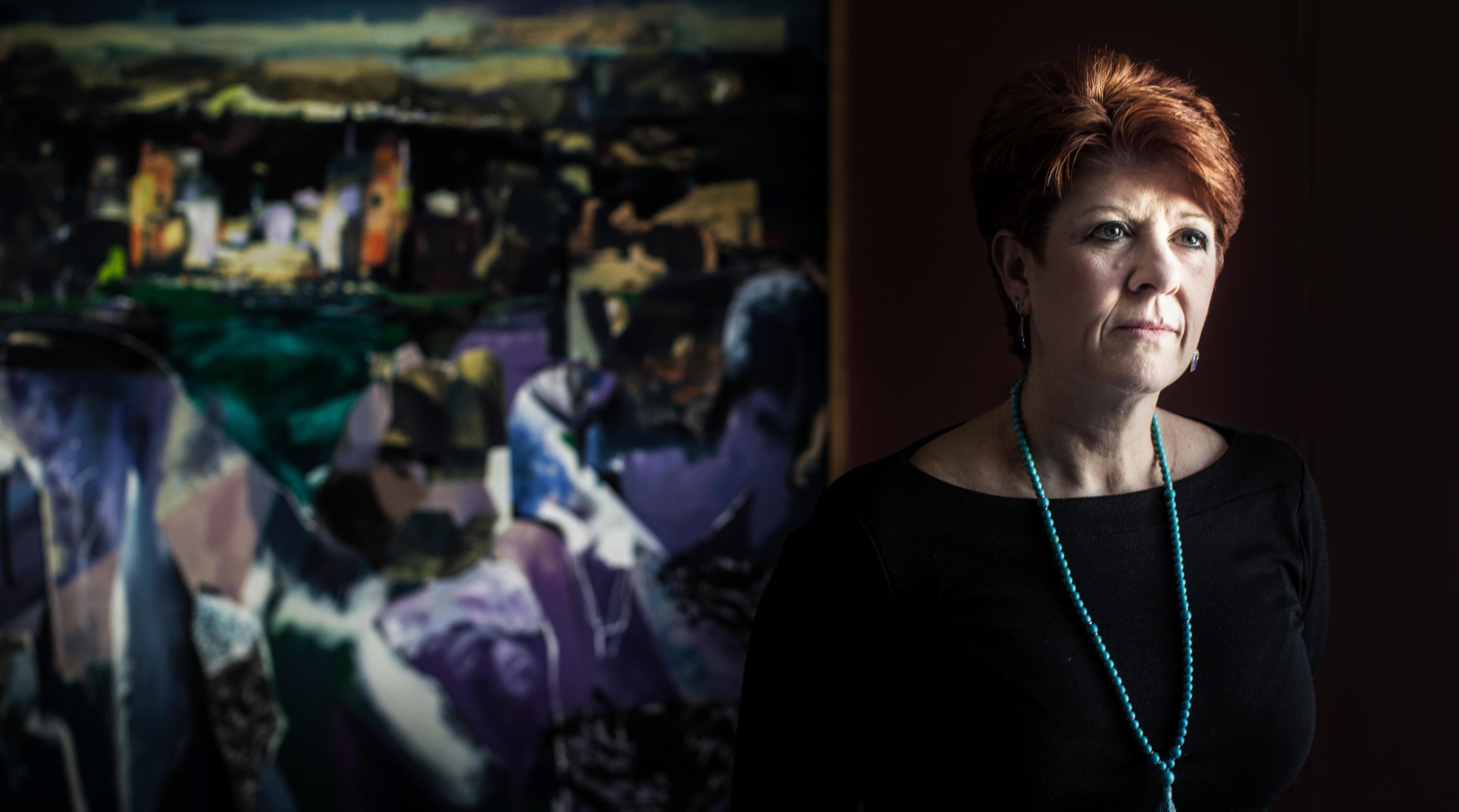 A woman with red hair standing in front of artwrok