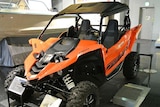 An orange and black all terrain vehicle on display