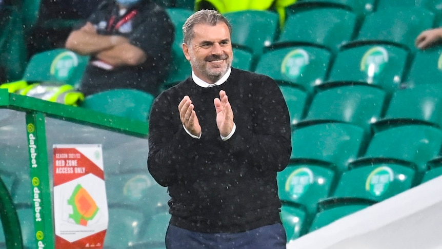 Celtic football manager smiling and capping after winning a match