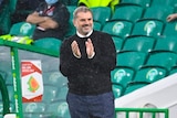 Celtic football manager smiling and capping after winning a match