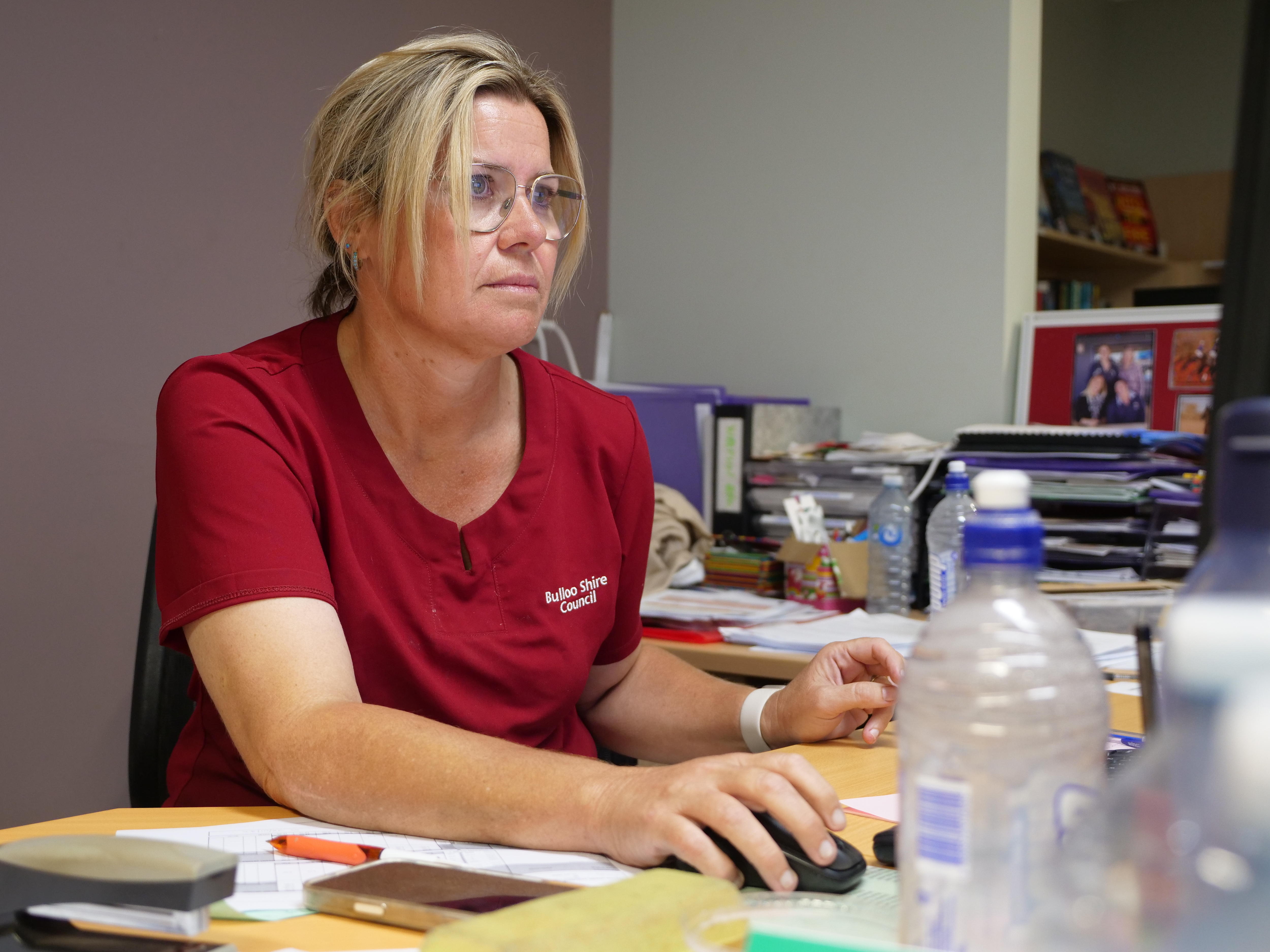 Uma mulher sentada em uma mesa em frente a um computador