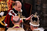 The Prince of Wales touches St Edward's Crown on King Charles III's head.