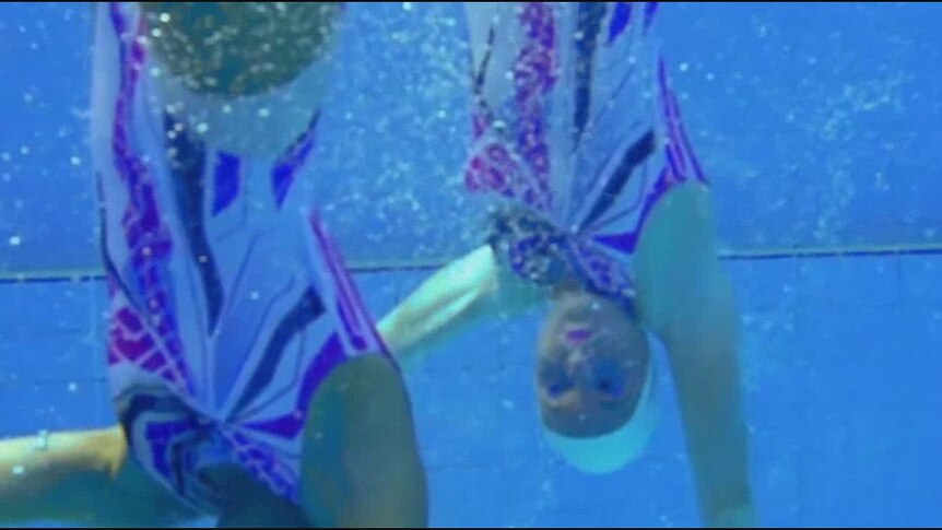 Two artistic swimmers underwater, they are required to hold their breath for up to a minute