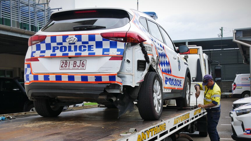 A damaged police car on the back of a tow truck 