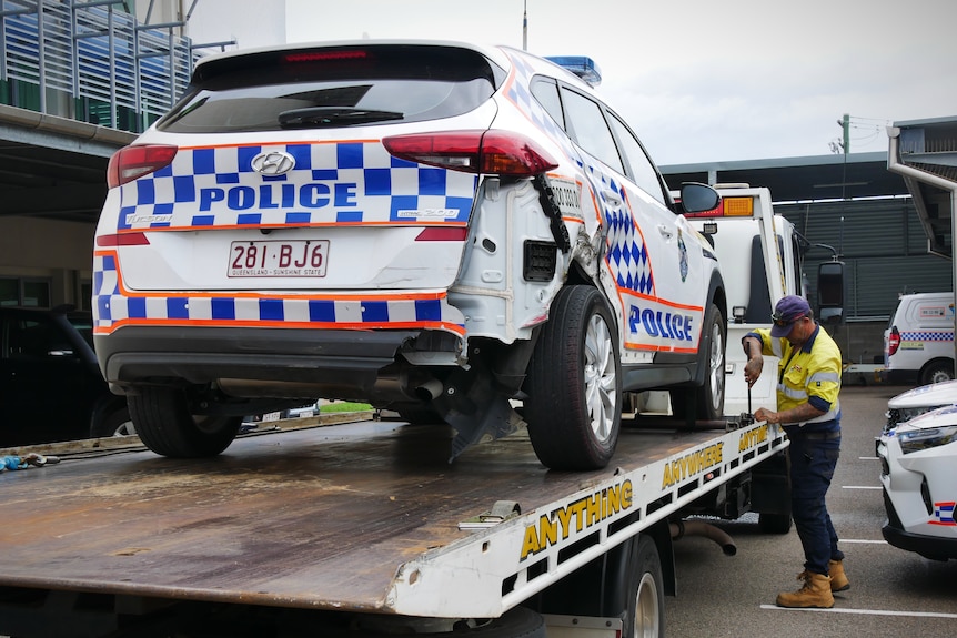A damaged police car on the back of a tow truck 