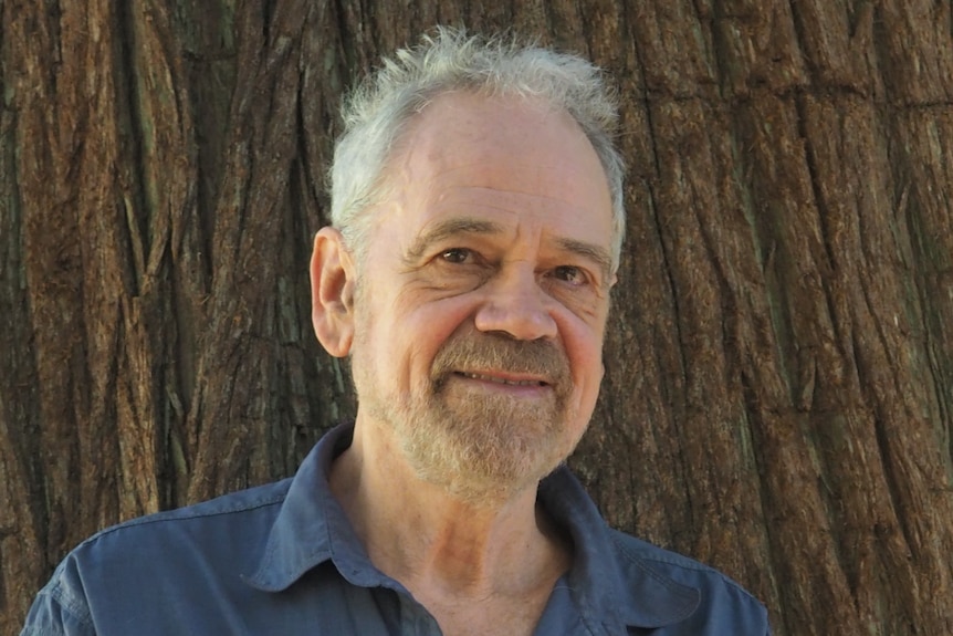 A man stands in front of a tree